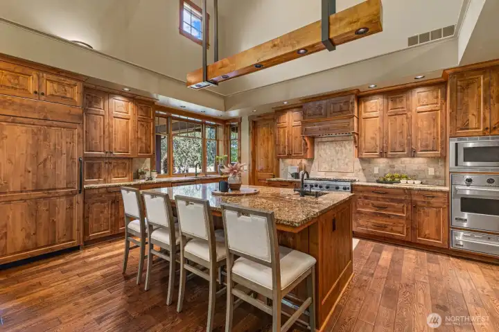 Beautiful custom knotty pine cabinetry — including paneled refrigerator fronts — complements a generous pass-through window to the patio and a large walk-in pantry with Sub-Zero freezer.