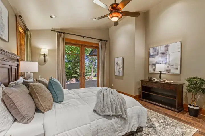 Spacious main-floor primary suite with oversized walk-in closet and luxurious travertine bath with heated flooring featuring slab-granite countertops. Sun-filled glass doors open to a large patio with serene golf-course views, blending comfort and elegance.
