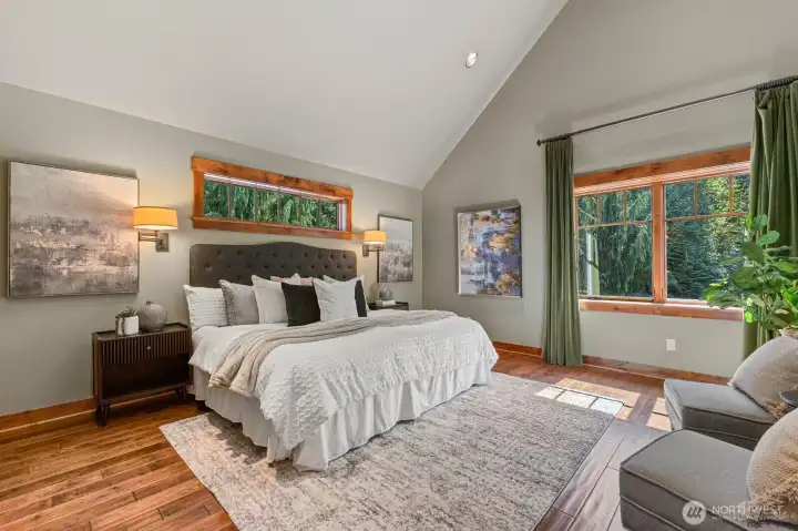 Sophisticated upper-level master with soaring arched ceiling, rich knotty-pine hardwood floors, and solid wood doors. Built-in, recessed chest of drawers adds bespoke, high-end functionality, while a personal thermostat ensures comfort tailored to your preference.