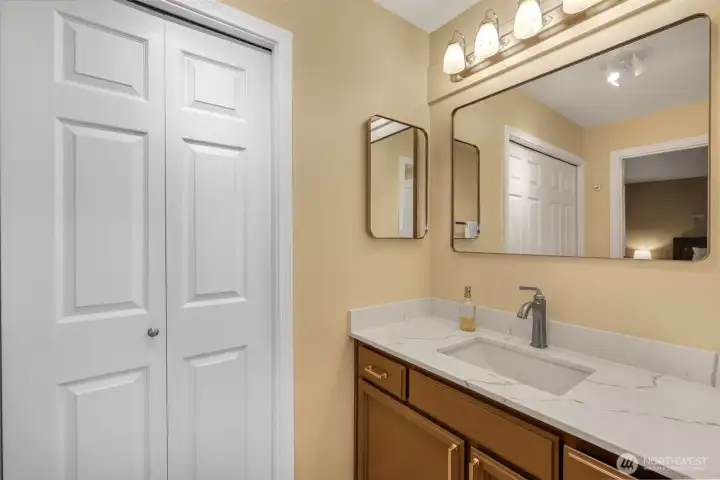 The ensuite bath offers a vanity with a solid-surface countertop and updated fixtures. Bright lighting and a functional layout make getting ready easy and comfortable.