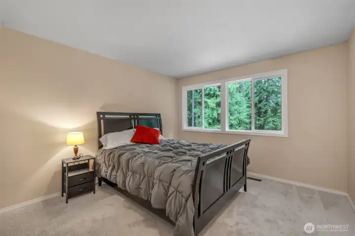 One of the additional bedrooms provides flexibility as a guest room, home office, or personal retreat. Large windows overlook the treetops, enhancing the quiet, peaceful setting.