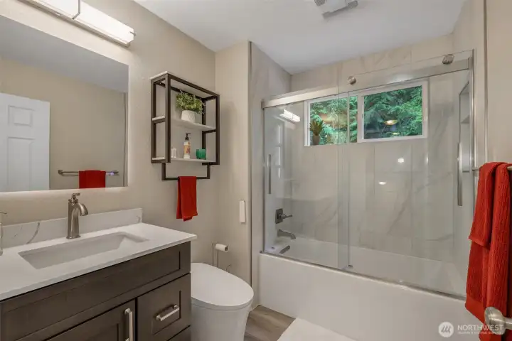 The main full bath has been beautifully updated with a sleek vanity, quartz countertop, and modern fixtures. A large mirror and stylish lighting enhance the fresh, contemporary feel.