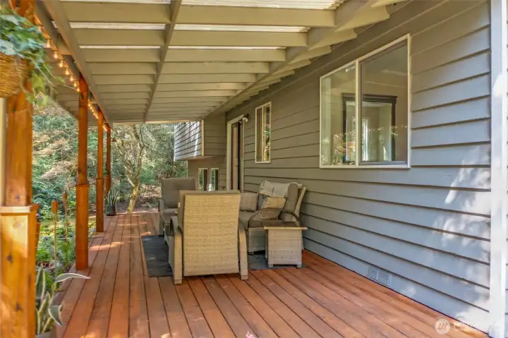 Another angle of the covered deck highlights the tranquil forested backdrop. Whether enjoying morning coffee or evening gatherings, this private setting enhances the property’s retreat-like feel.