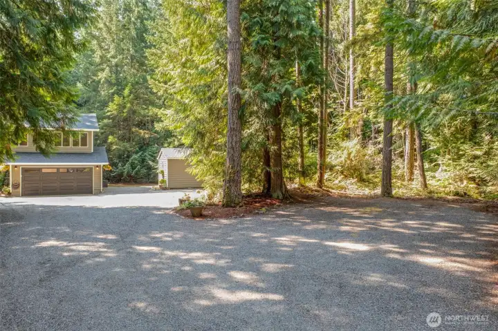 The large driveway leads to the two-car garage with additional space for parking. A detached shed provides extra storage, adding to the property’s functionality.