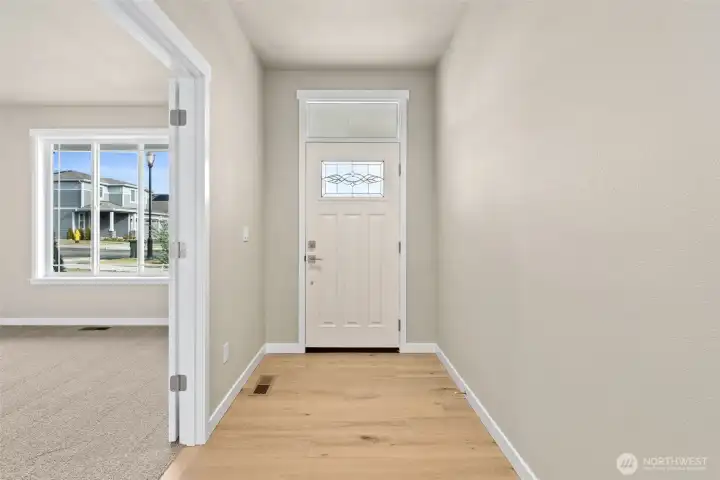 Entryway featuring hardwood floors extended through hallway.