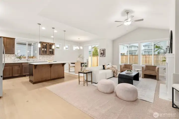 Light and bright open living room with vaulted ceilings and ceiling fan.