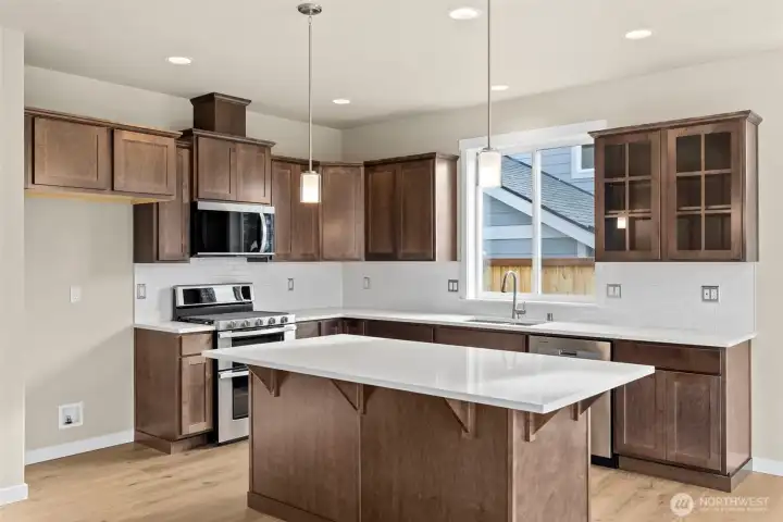 Kitchen features Cocoa-stained Maple Cabinets and Quartz countertops.  Whirlpool stainless steel gas double oven is standard.