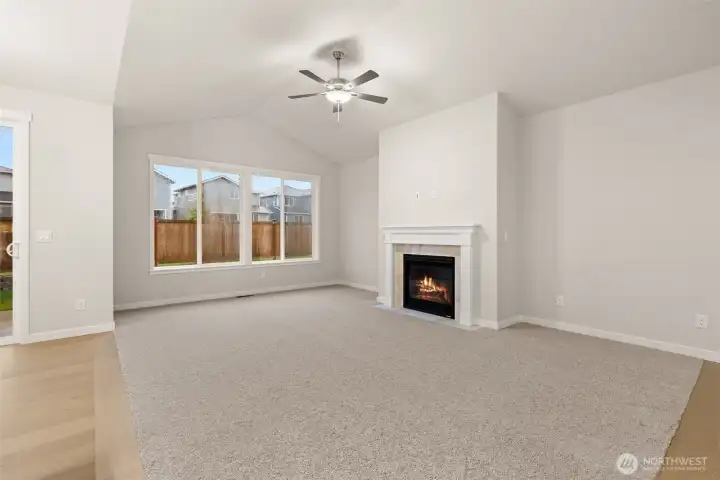 Light and bright open living room with vaulted ceilings and ceiling fan.