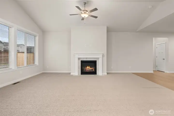 Light and bright open living room with vaulted ceilings and ceiling fan.