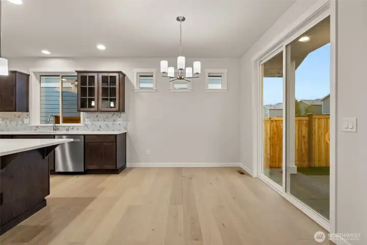 Dining area features hardwood flooring and a glass slider that opens to backyard and patio area.