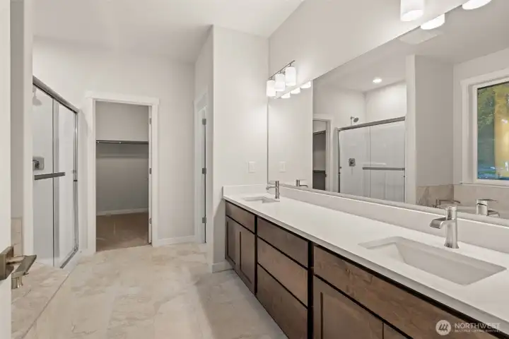 Primary bath is stunning with a double vanity with undermount sinks and tile backsplash.