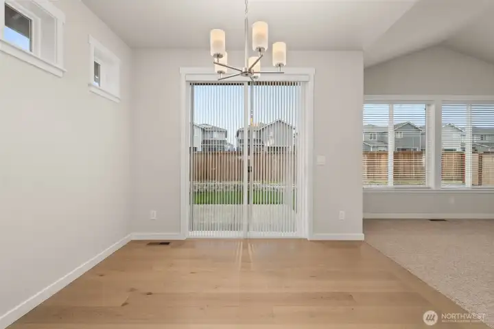 Dining area features hardwood flooring and a glass slider that opens to backyard and patio area.