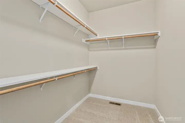 Primary closet is walk-in with extra storage shelves above the hanging rods.