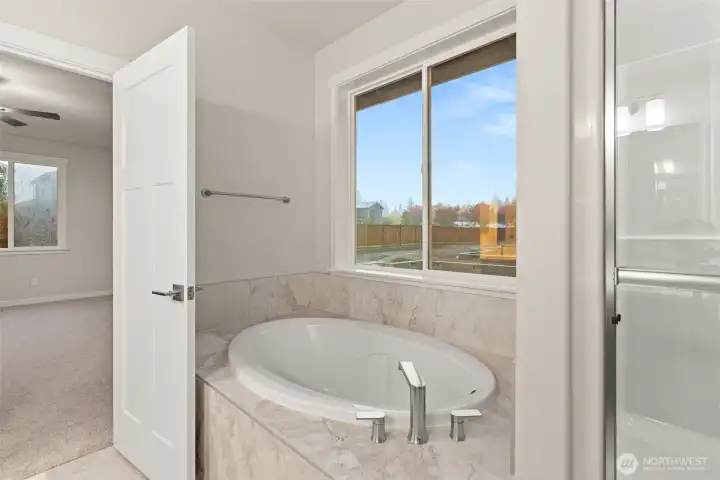 Primary bath also offers a beautiful, large soaking tub with tile surround.