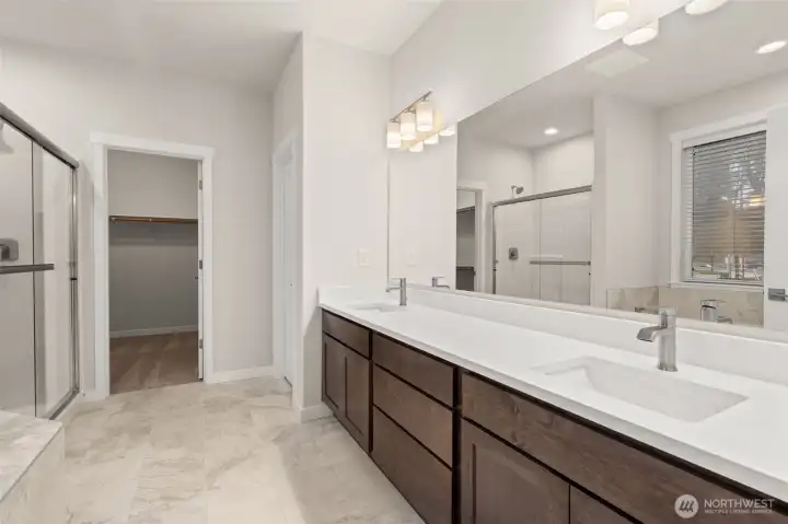 Primary bath is stunning with a double vanity with undermount sinks and tile backsplash.