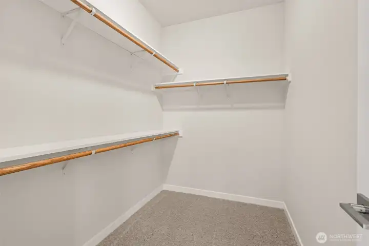 Primary closet is walk-in with extra storage shelves above the hanging rods.