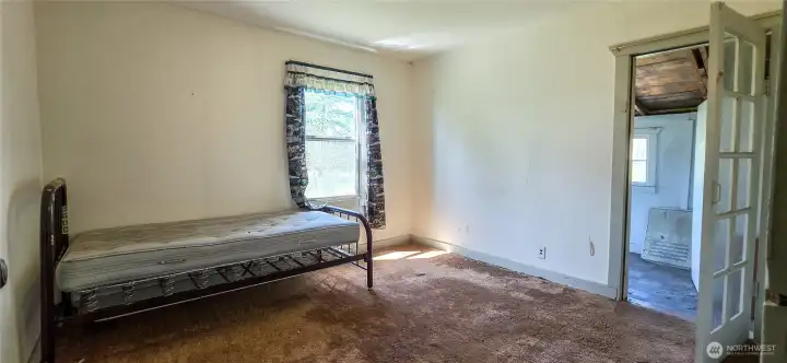 Bedroom 2 is located in the Northwest area of the home, completing the comfortable West-side sleeping quarters alongside the shared full bathroom. The door leads to a bonus room with access to the mudroom.