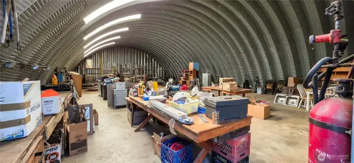 Inside the 40 x 60 Quonset hut: Very tall ceilings easily accommodate a car lift, RV, or large toy storage. The highly functional layout features a 2/3 poured concrete floor with a 1/3 dirt floor at the back. Looking West from the East side.