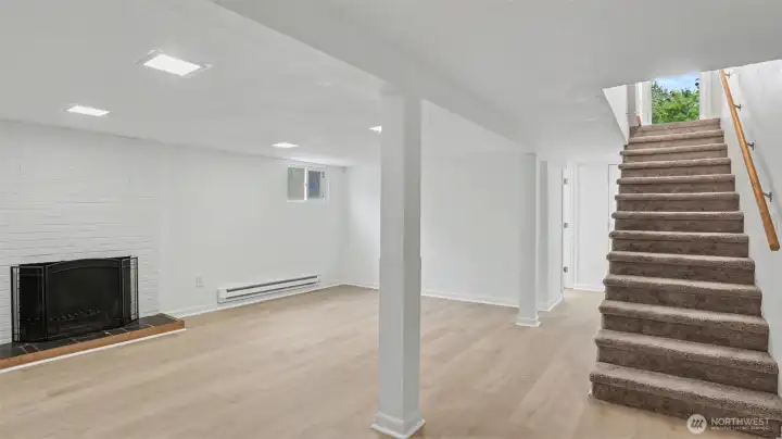Coming down the stairs into the finished basement's spacious bonus room with wood-burning fireplace.
