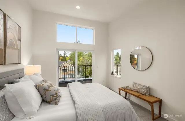 Serene bedroom with high ceilings, large windows, and a balcony, creating a dream restful retreat.