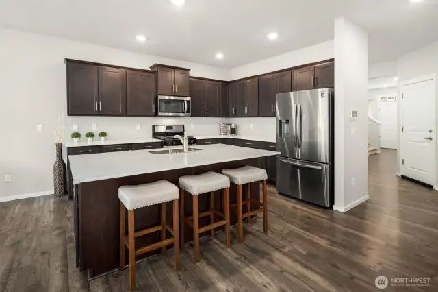 Enjoy this beautiful kitchen design with breakfast bar area at the island, quality appliances, plenty of storage space, and a pantry closet to the right side of the hallway.