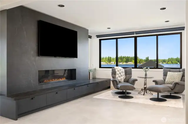 Here’s the great room with another of the 4 fireplaces boasting built ins for storage and a picturesque morning on Lake Sawyer