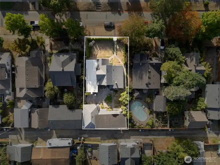 Aerial view of the property showcasing the fully fenced yard, lush landscaping, detached shop, covered carport, and overall lot layout in the desirable Edison District.