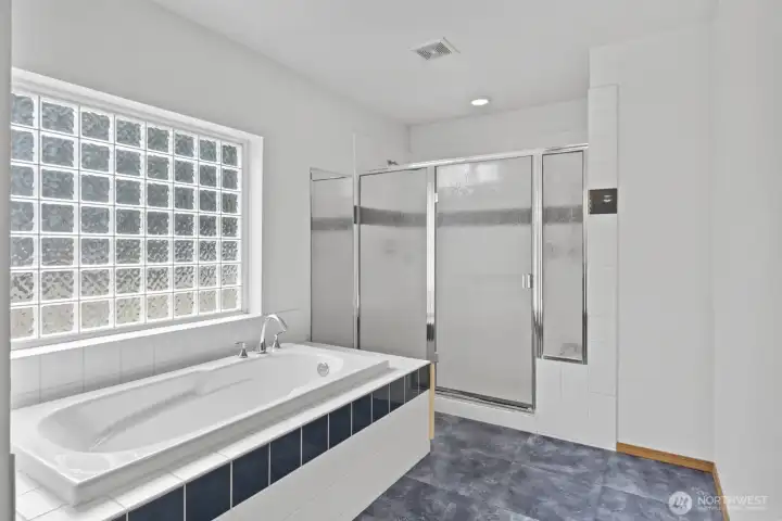 The soaking tub and shower with double shower heads are surrounded by tile.