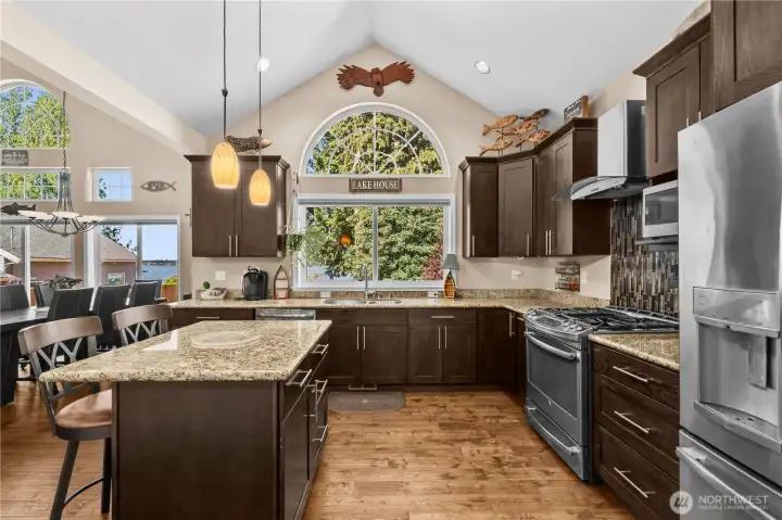 Chef's kitchen with vaulted ceilings, island, granite and stainless steel appliances.