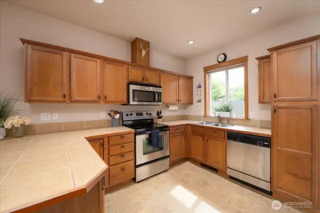 At the top of the stairs just to the left is this spacious kitchen as well as a 1/2 bath and outside deck.  Lots of light year round. So much storage and SS appliances all stay!