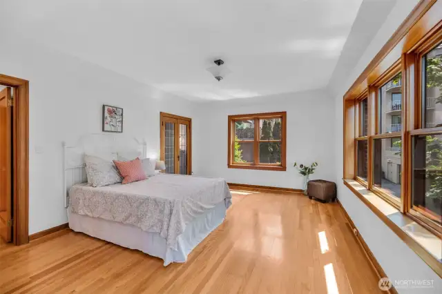 Walls of windows & hardwood floors glow with natural light.