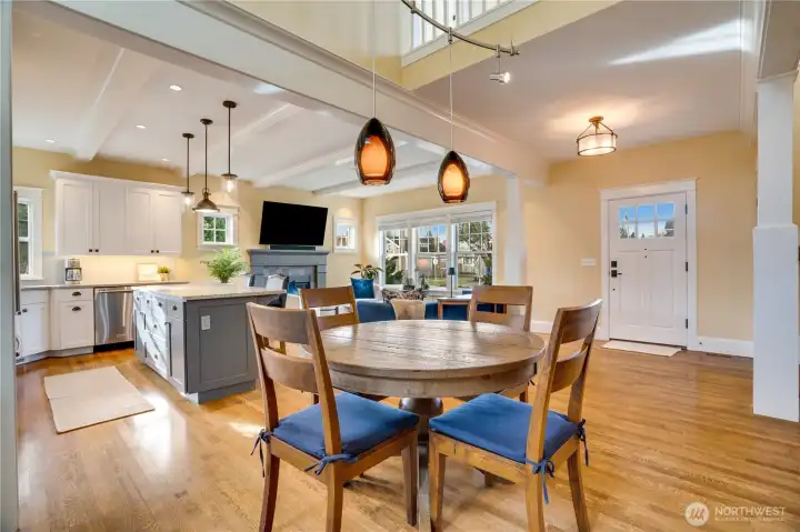 The dining area is framed by beautifully finished beams with crown molding details and features a soaring ceiling with pendant lighting—an inviting spot for meals or game nights with friends.