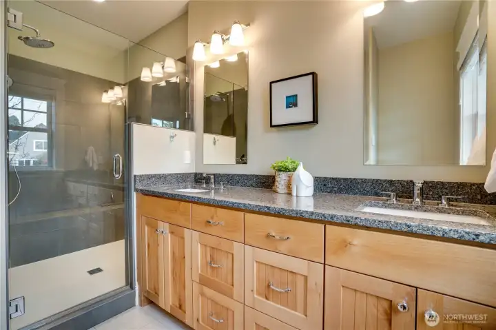 The primary bath features a large quartz-topped vanity, abundant storage, and a heated tile floor for year-round comfort.