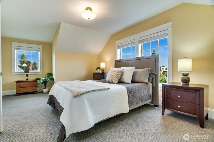 Large wood-wrapped windows bathe this room in natural light. Plush carpeting, refined window coverings, and elevated finishes showcase the consistent quality carried into every upstairs space.