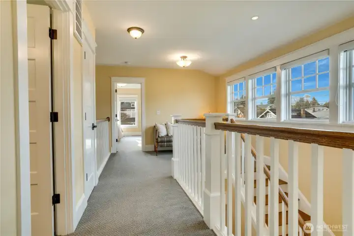 The upper hall, with natural light, handcrafted railings, and an overlook of the dining room, enhances the home’s sense of flow and spaciousness.