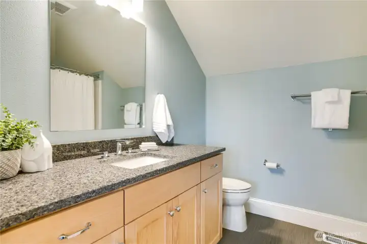 A bright and roomy full bath with ample counter space and plenty of storage. Quartz counters and tile floors add durability and a refined finish.