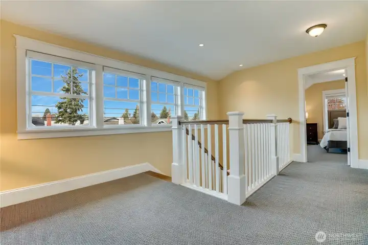 A wall of windows brightens the landing with natural light. Upgraded window coverings add both style and privacy.