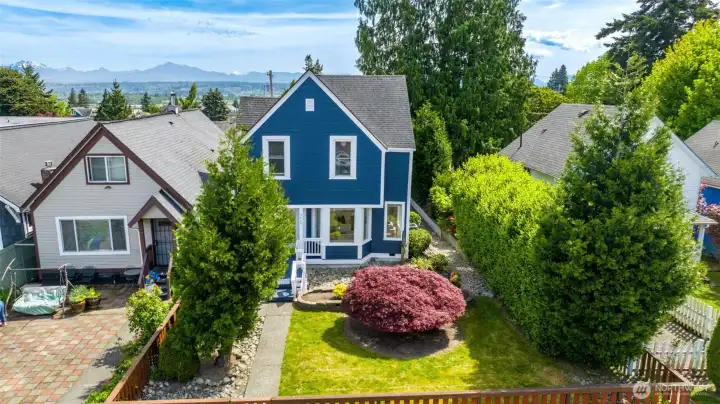 This photo shows the beautiful grassy area in the front yard. The yard is partial fenced and features some river rock decor and a gorgeous Japanese maple tree.