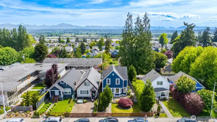 This is an drone photo looking at the front of the home with the Cascade Mountains in the distance.