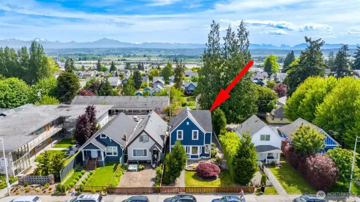 This is an drone photo looking at the front of the home with the Cascade Mountains in the distance.