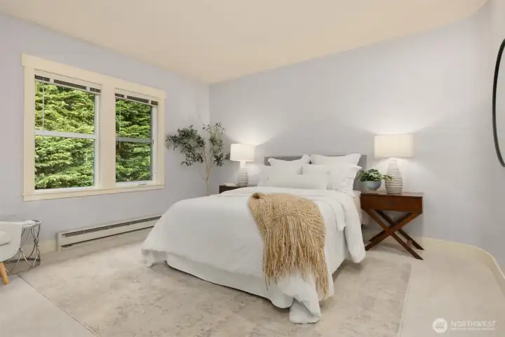 The well-proportioned primary bedroom features generous living space and calming views of mature trees just beyond the windows.