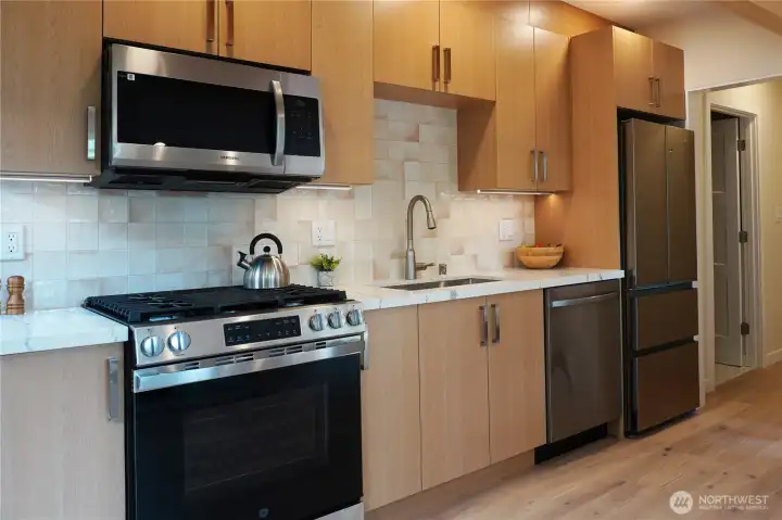 Gas stove, custom cabinets and tile in kitchen.
