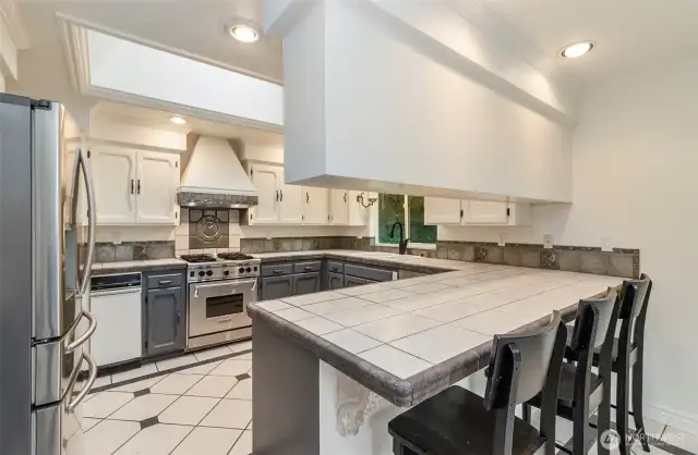 Custom Kitchen Accents Gleam Under the Oversized Skylight in the Kitchen~Fresh Updated Two Tone Painted Cabinets~Beautifully Tiled Flooring~Backsplash~Countertops & Exhaust Hood~Cook it & They will Come~