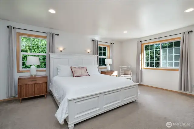 The primary bedroom features corner windows that flood the space with natural light, creating a warm and airy retreat perfect for relaxation.