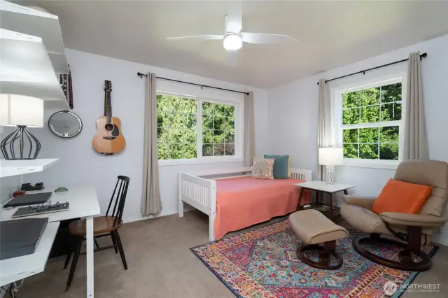 This second-story bedroom features corner windows that welcome abundant morning sunlight, creating a bright and cheerful space to start the day.
