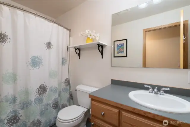 The second-story bathroom offers a fresh, bright space featuring a combined shower and tub.