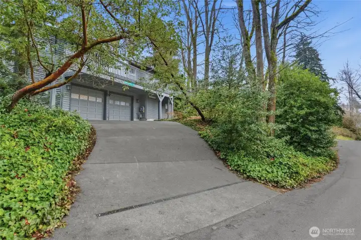Two-car driveway with garage access nestled in lush, low-maintenance landscaping.