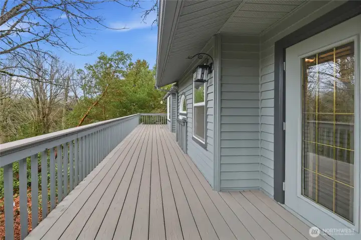 Primary suite deck access features low-maintenance composite surface surrounded by mature trees for natural privacy.