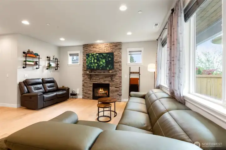 Wall to ceilings stone wall with gas fireplace and wall of windows looking out to the fully fenced backyard.