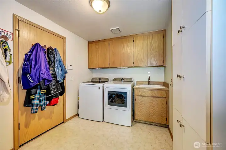 Main level walk in laundry room with a separate sink and built in cabinets.